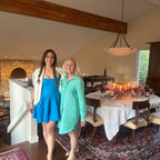 Two women standing in a dining room with a decorated table in the background