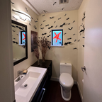 Bathroom with Halloween decorations, including bats on the wall and a red and blue ghost decoration.