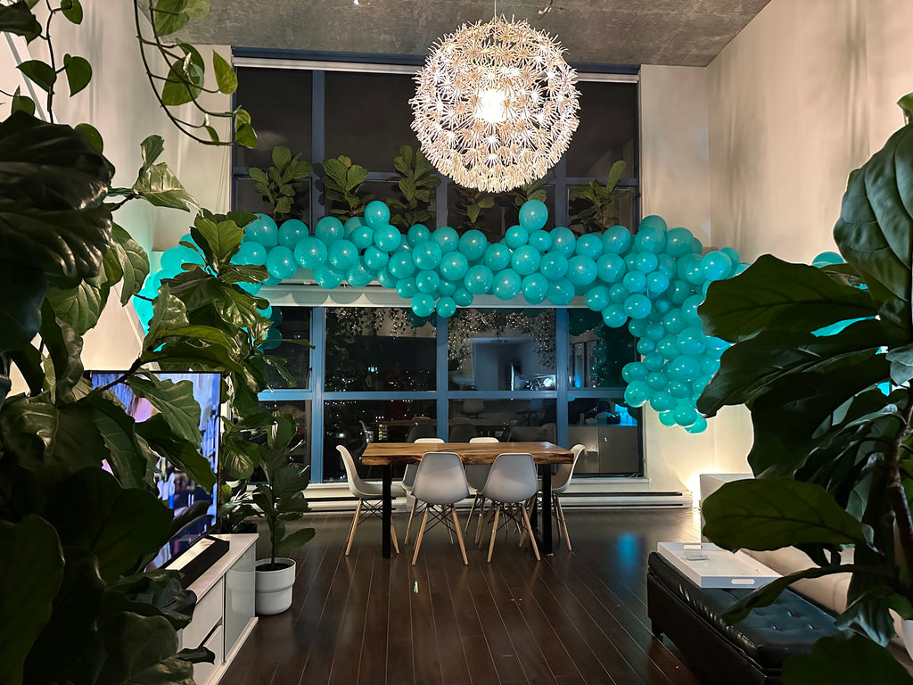 Modern interior with a blue balloon arch, dining table, and chairs.