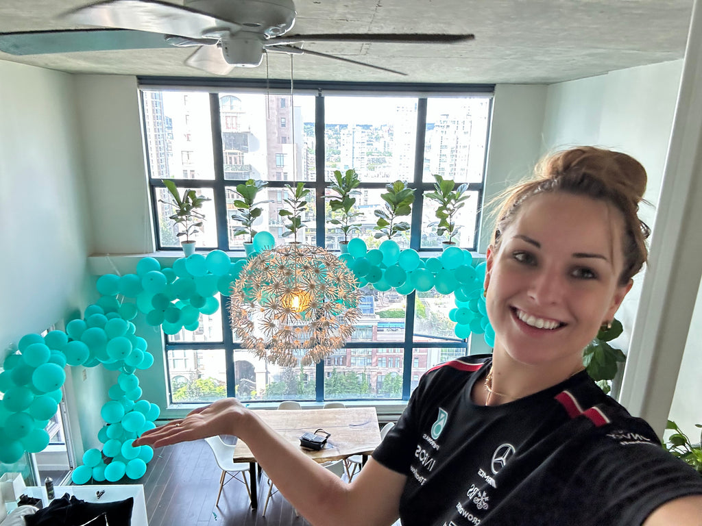 Woman in a room with teal balloon arch and decorative light fixture