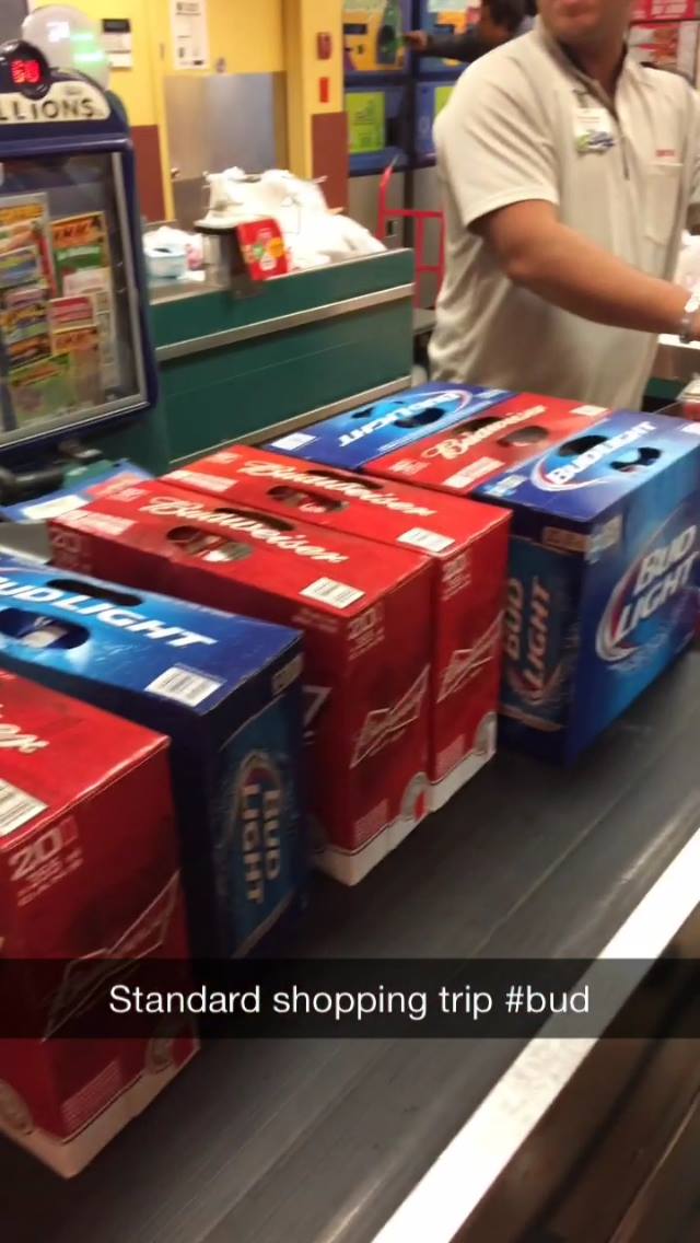 Bud Light beer boxes on a checkout counter with a person in a store.