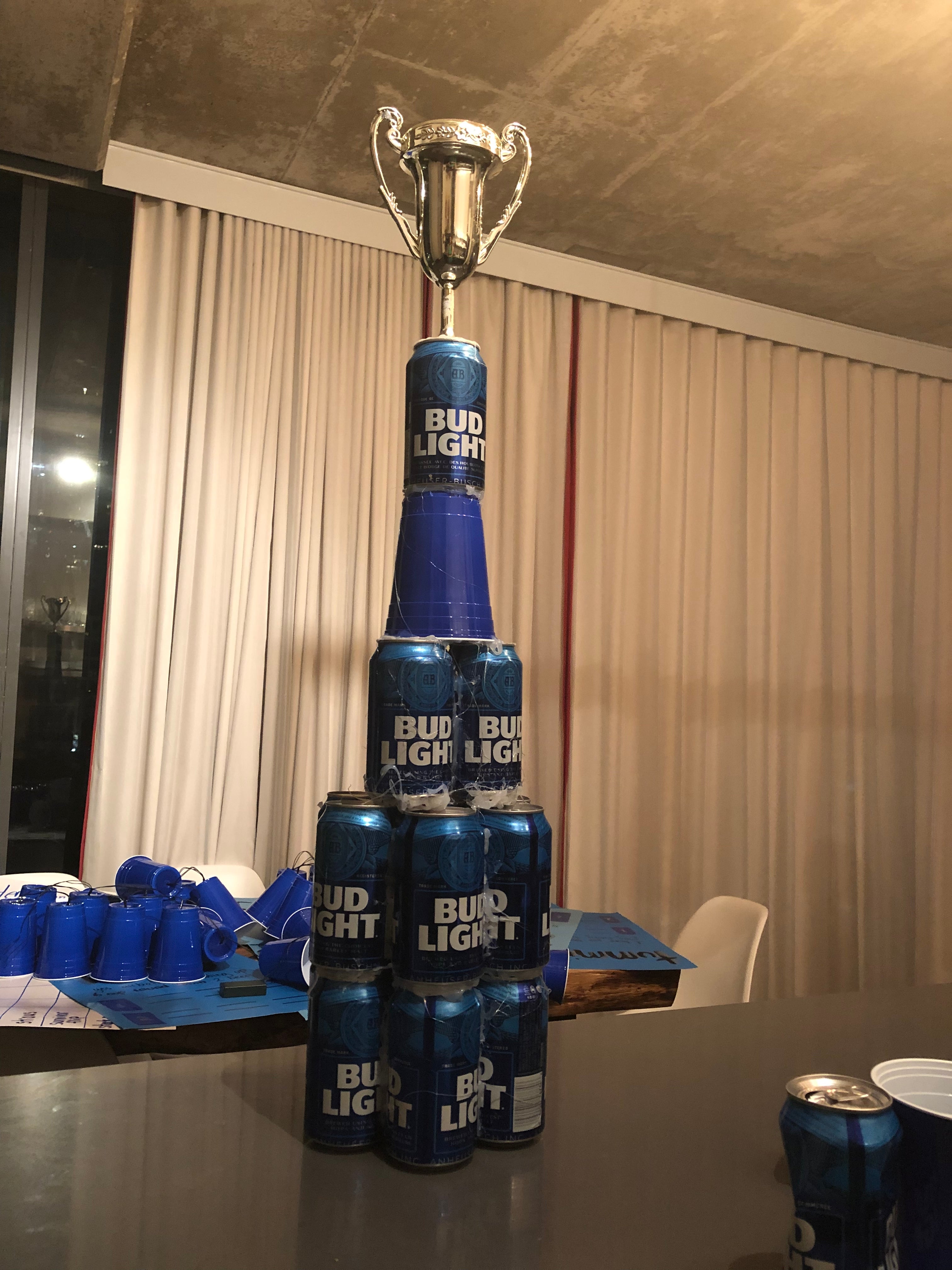 Bud Light bottles stacked with a trophy on top, against a neutral background