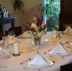 Dining table set with place settings, glasses, and a floral centerpiece.
