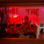 Decorative mirror with text and a person's reflection in a room with pink lighting.