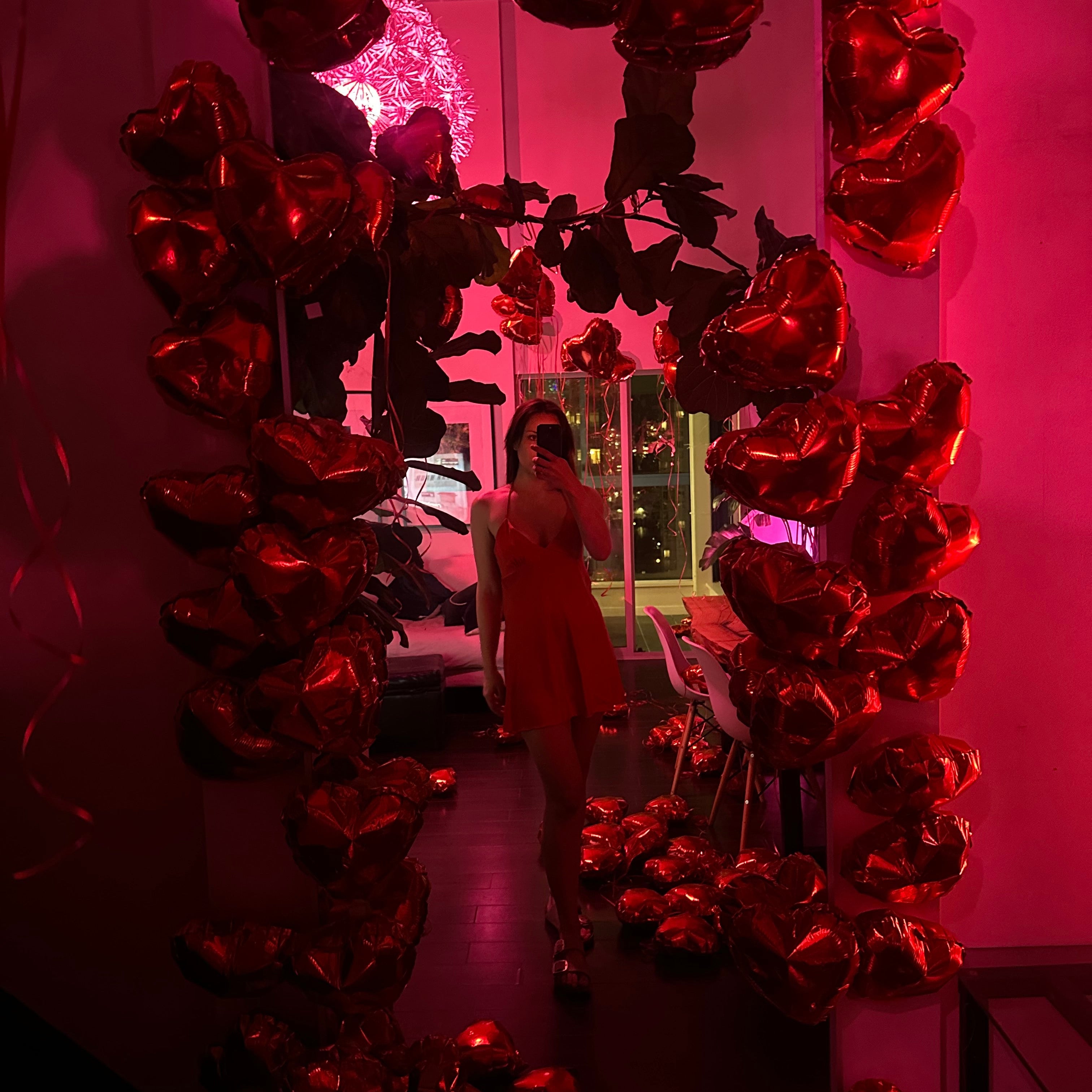 Decorative setup with red heart-shaped balloons surrounding a full length mirror girl taking reflection selfie photo 2