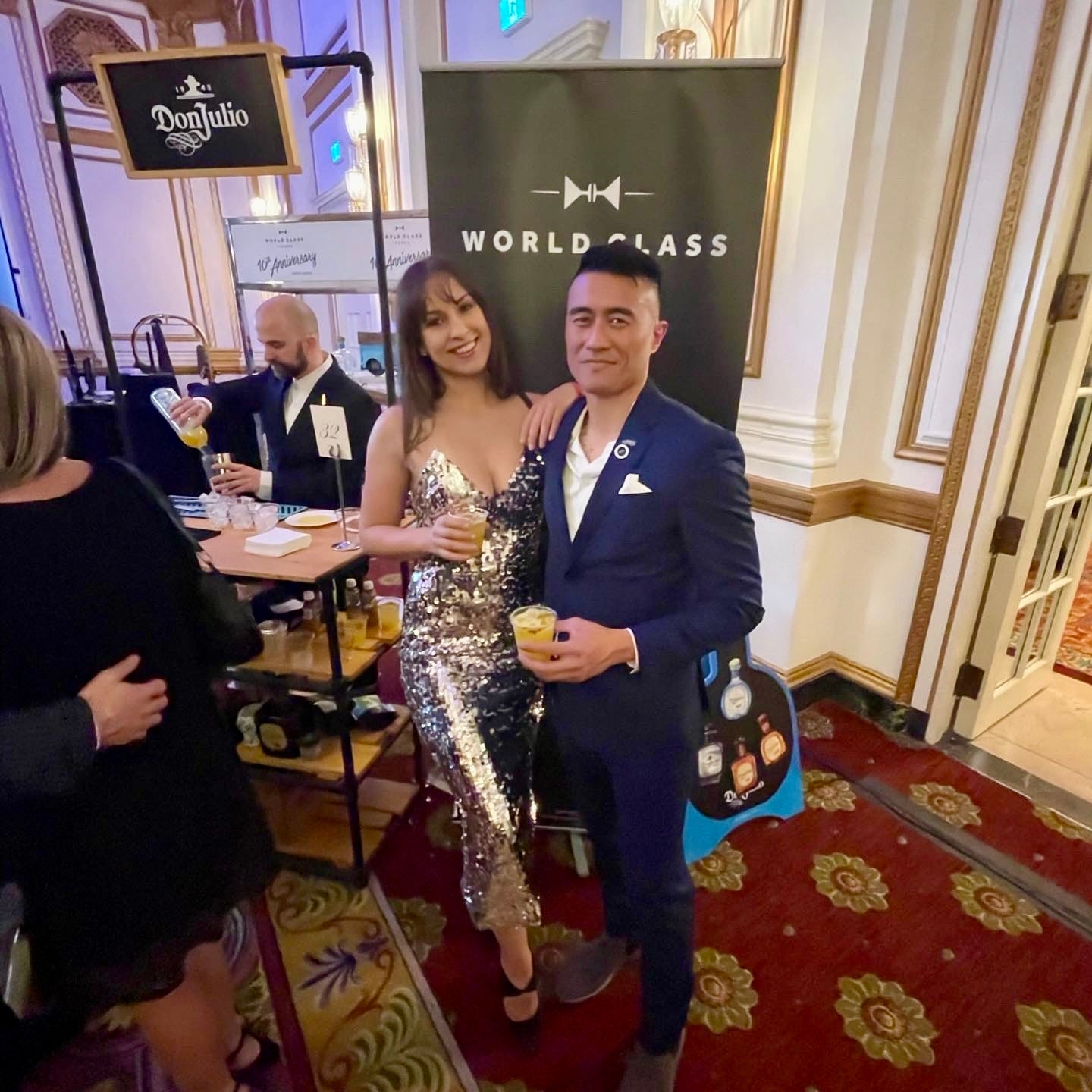 Two people posing in a formal setting with 'World Class' branding in the background.