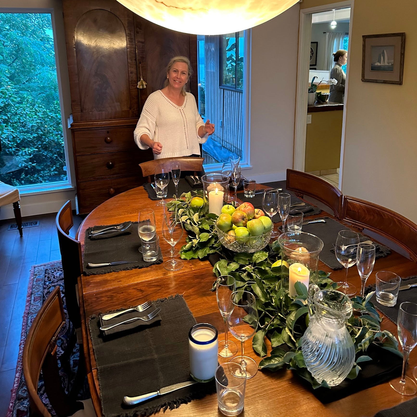 Dining room with a woman standing by a table set for a meal.