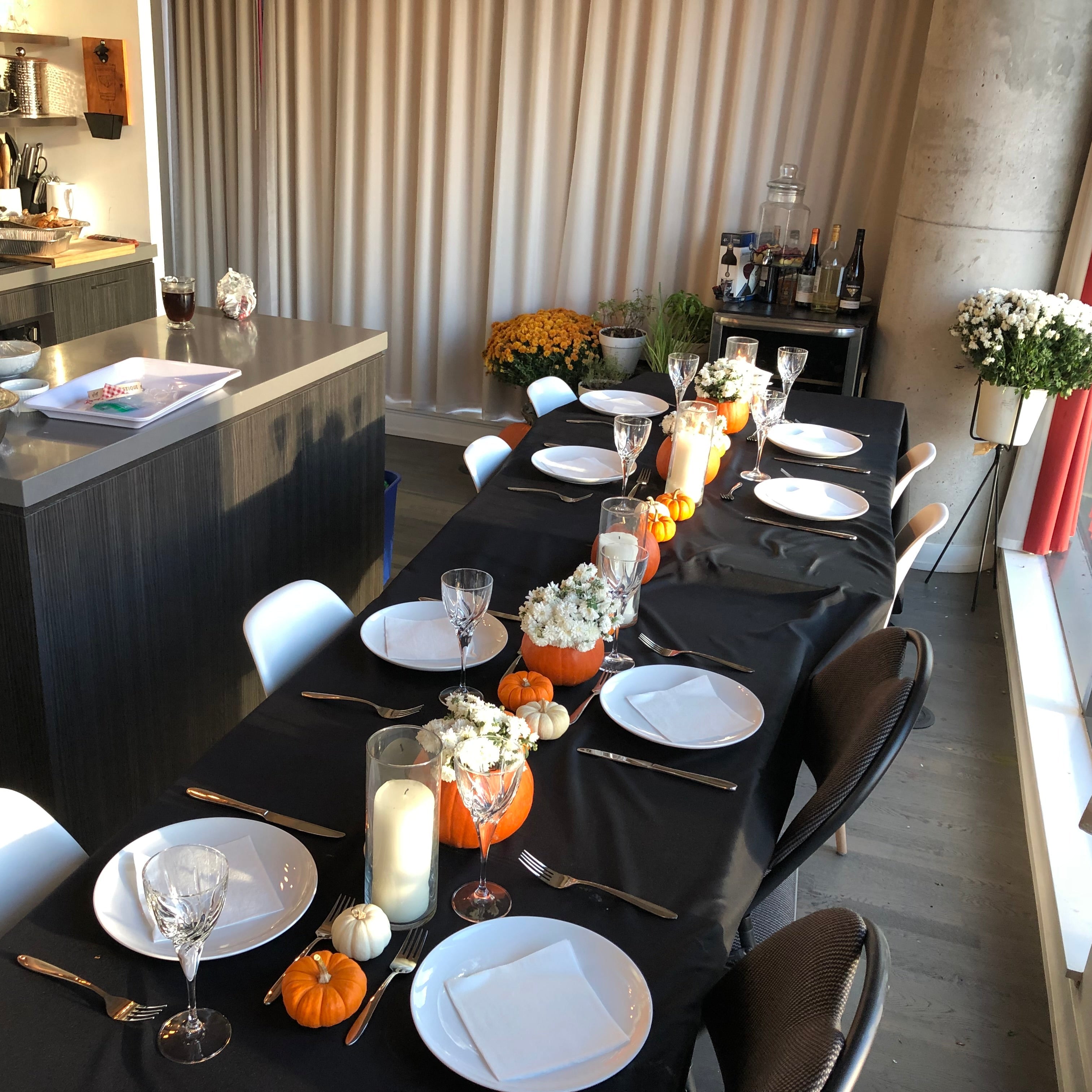 Dining table set for a meal with decorative pumpkins and candles in a modern kitchen.