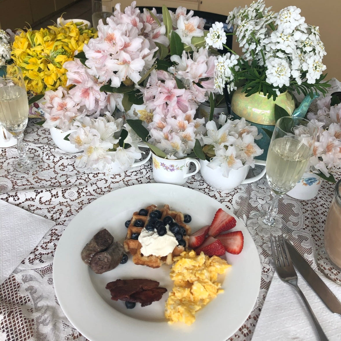 Dinner table set with a plate of food, flowers, and glasses in a kitchen setting.