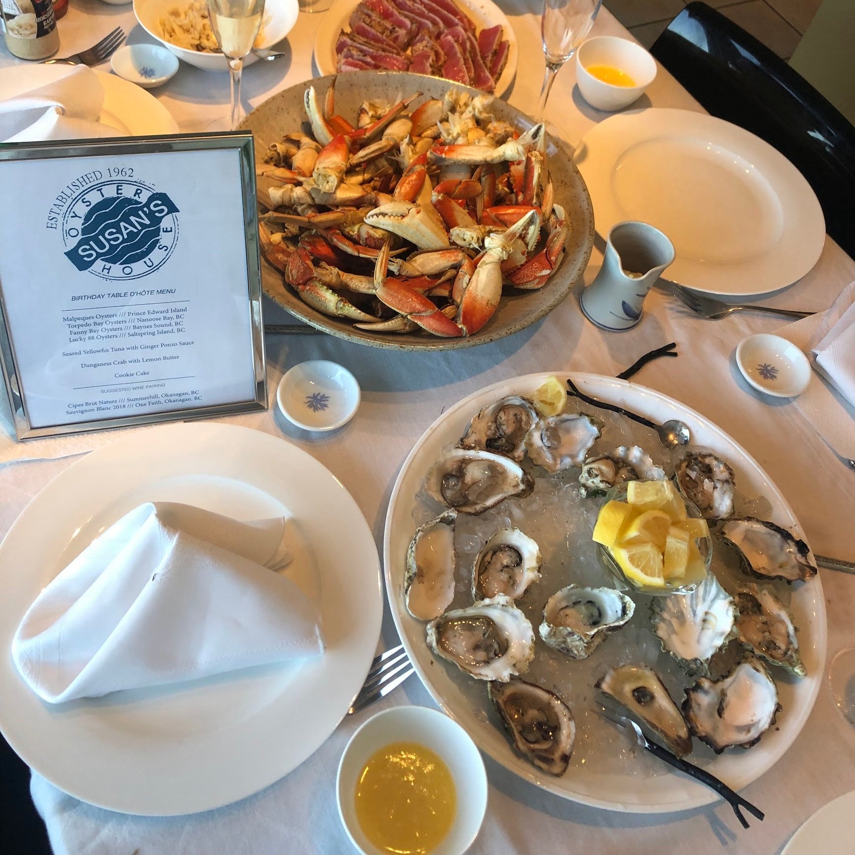 Dinner table set with seafood platter, oysters, and a menu at Susan's restaurant.