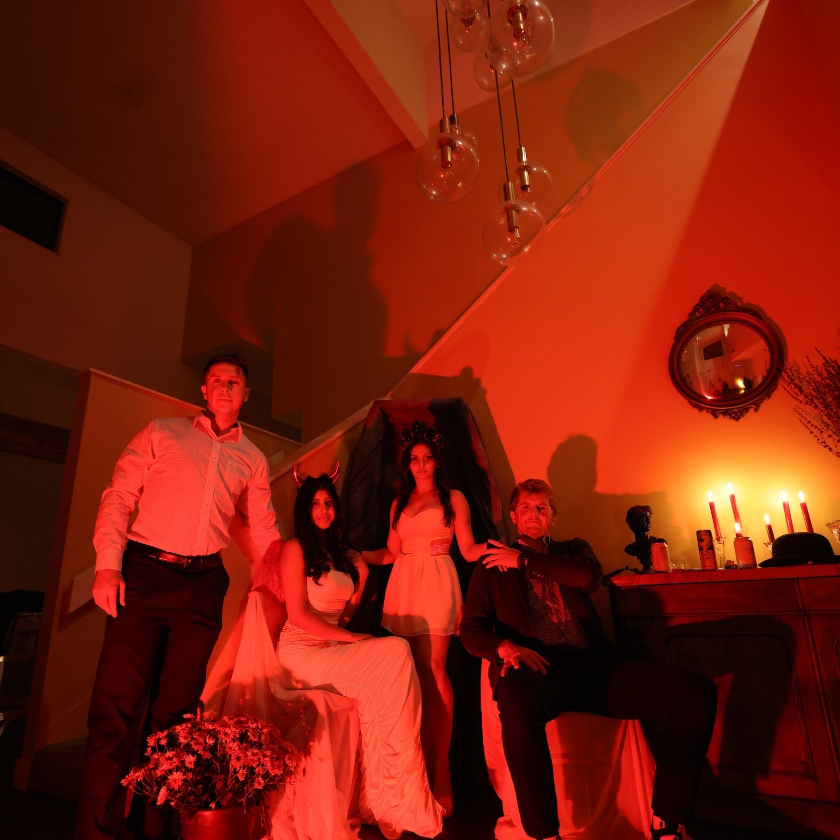 Group of people in a dimly lit room with red lighting, sitting around a table.
