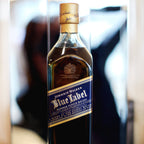 Johnnie Walker Blue Label whisky bottle on a reflective surface with blurred background