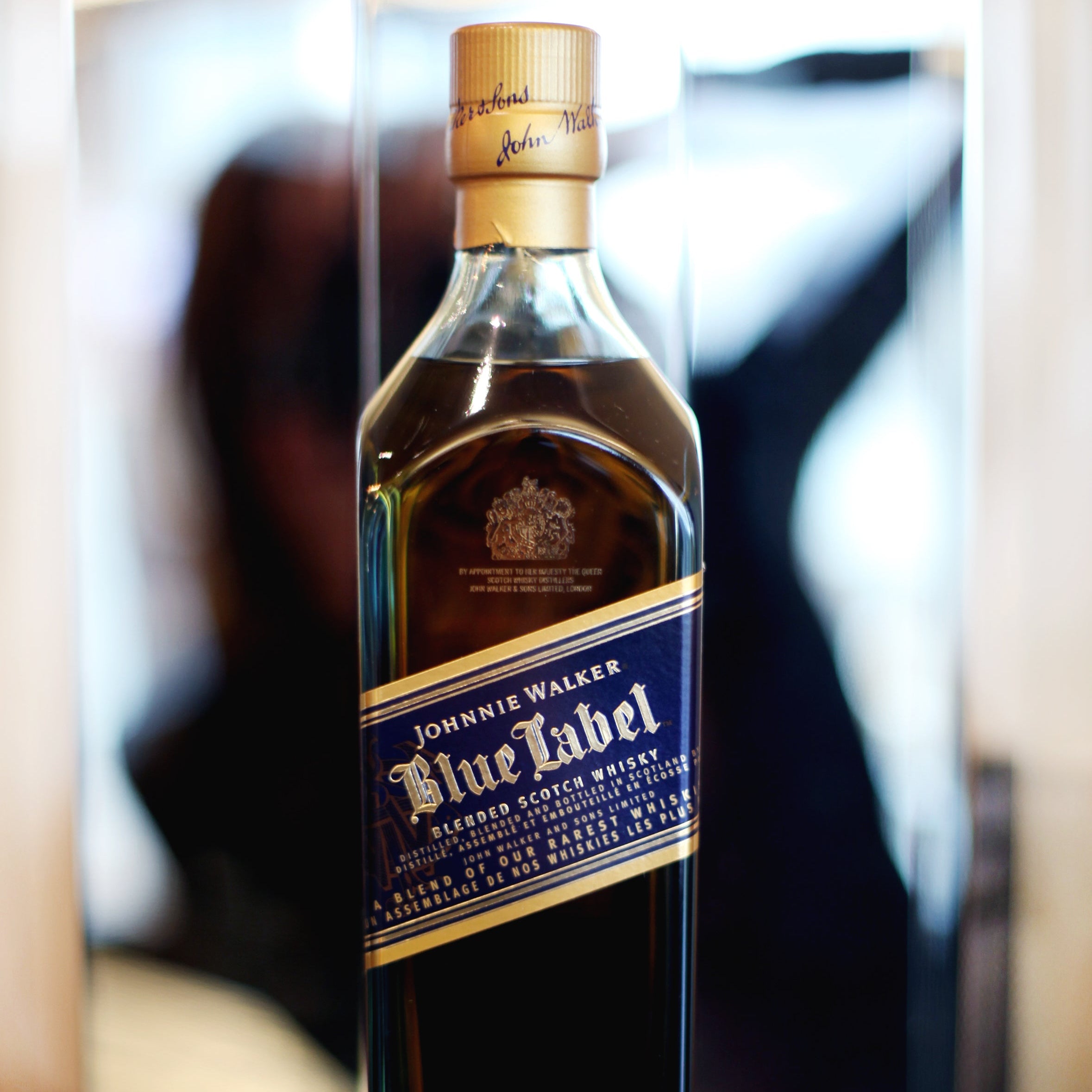 Johnnie Walker Blue Label whisky bottle on a reflective surface with blurred background