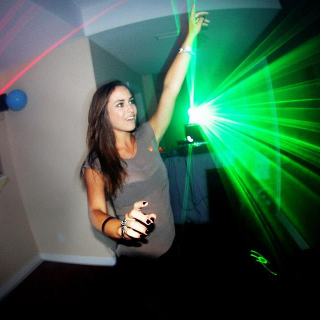 Person playing laser tag with red and green laser lights in a dark room.