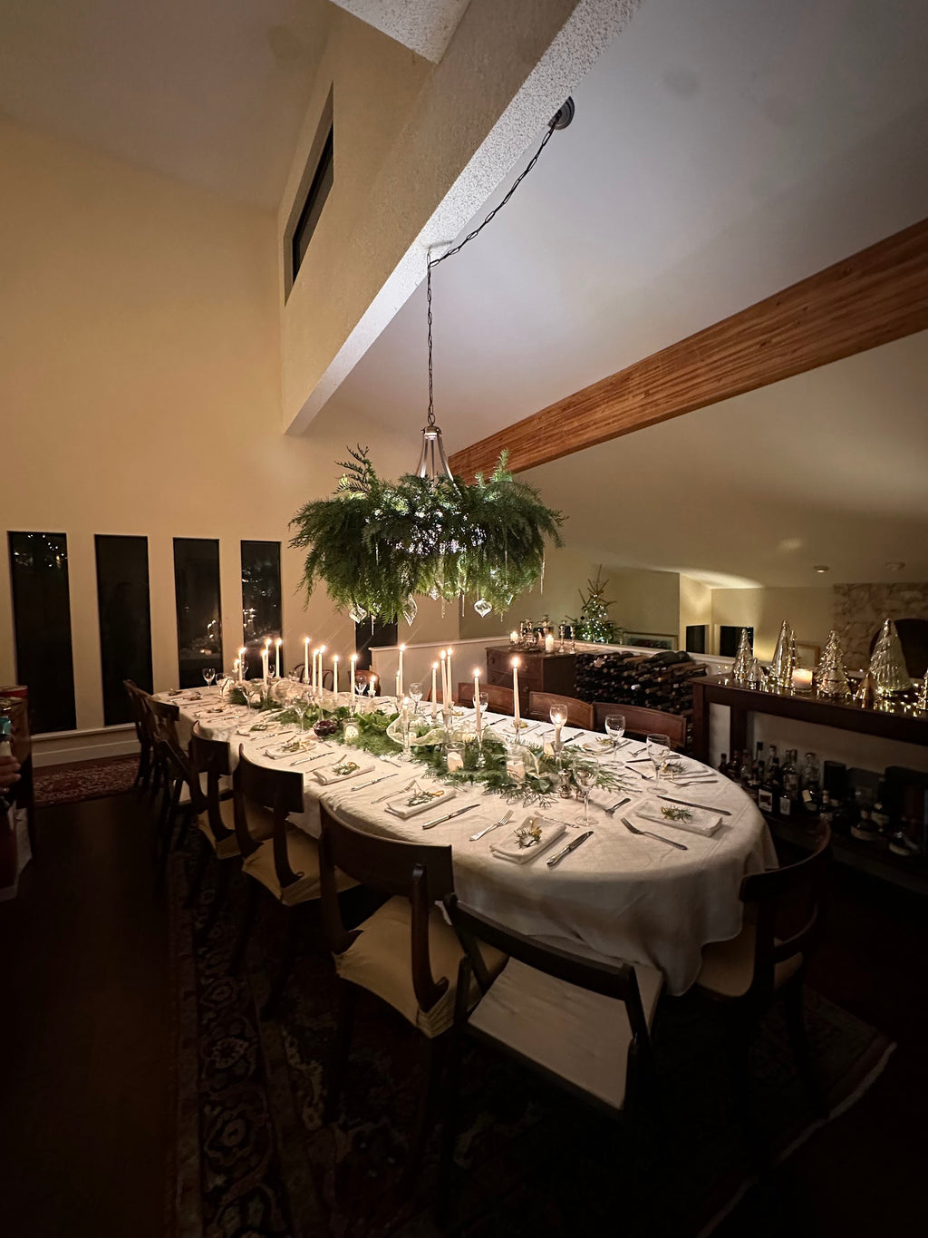 Dining room with a long table set for a meal, candles lit, and decorative elements.