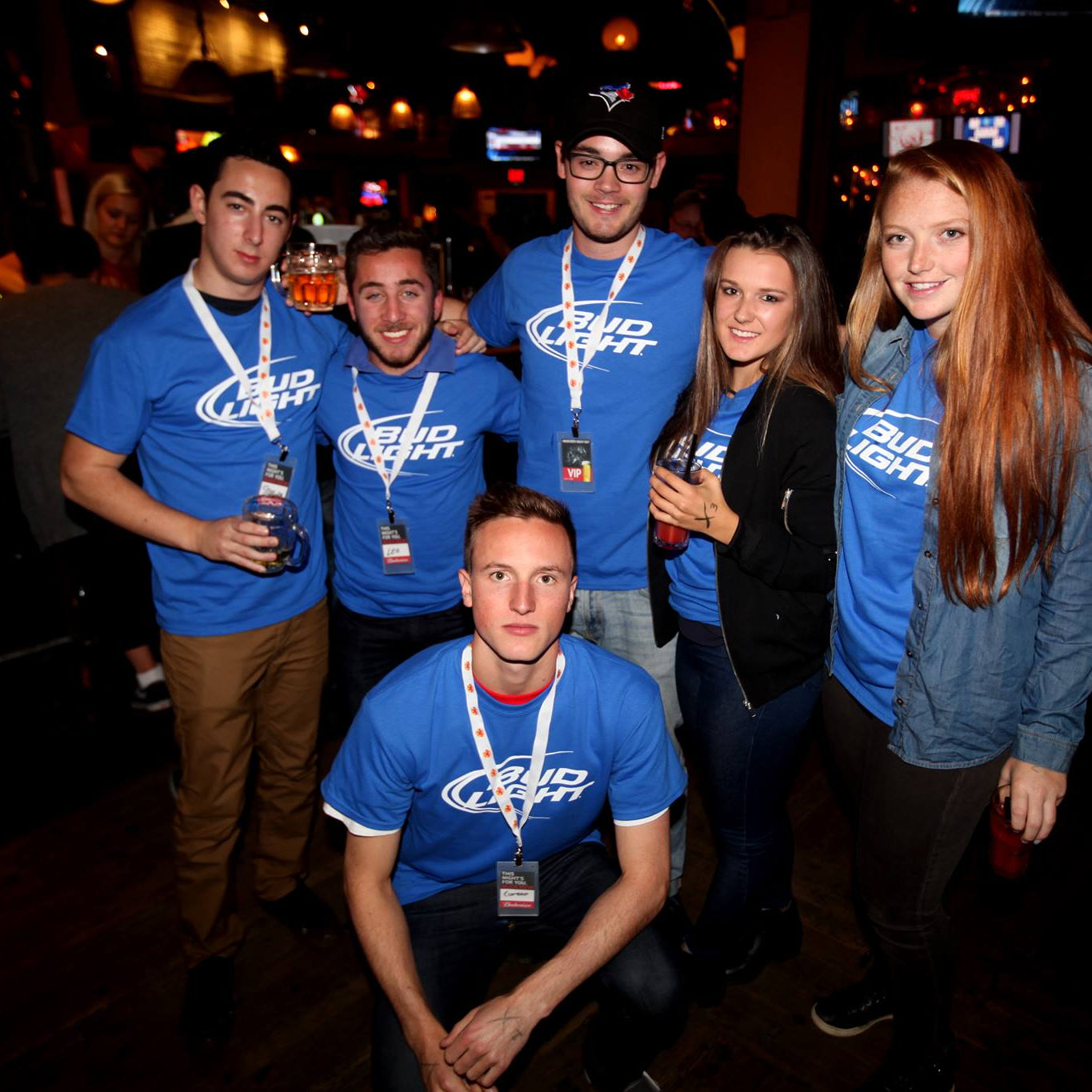 Group of people wearing Bud Light shirts in a bar setting