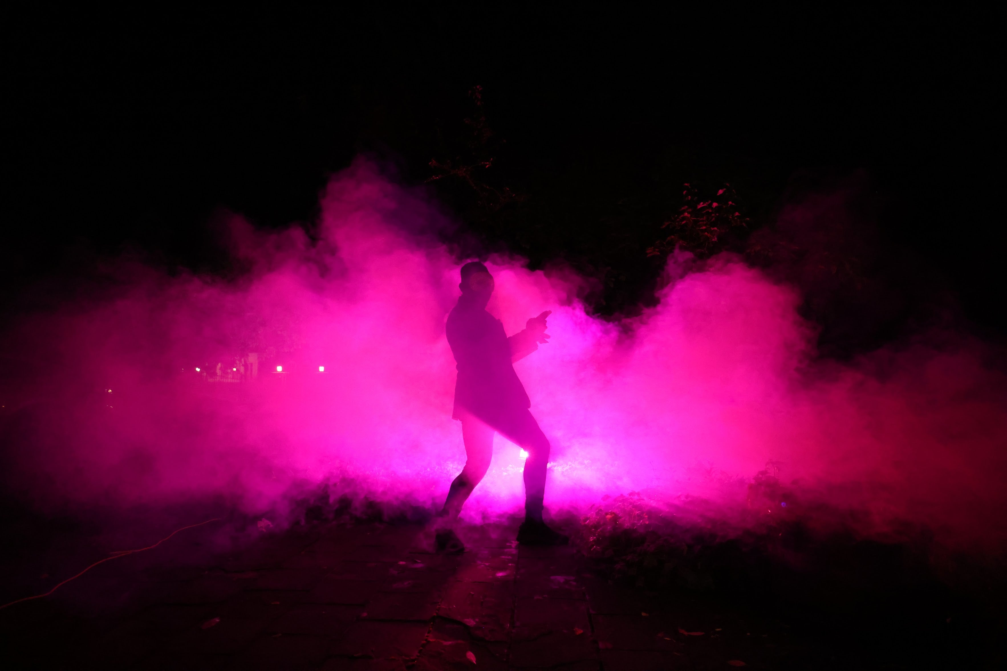 Person standing in pink smoke against a dark background