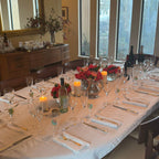 Dining room with a long table set for a meal, chairs, and decorative elements.