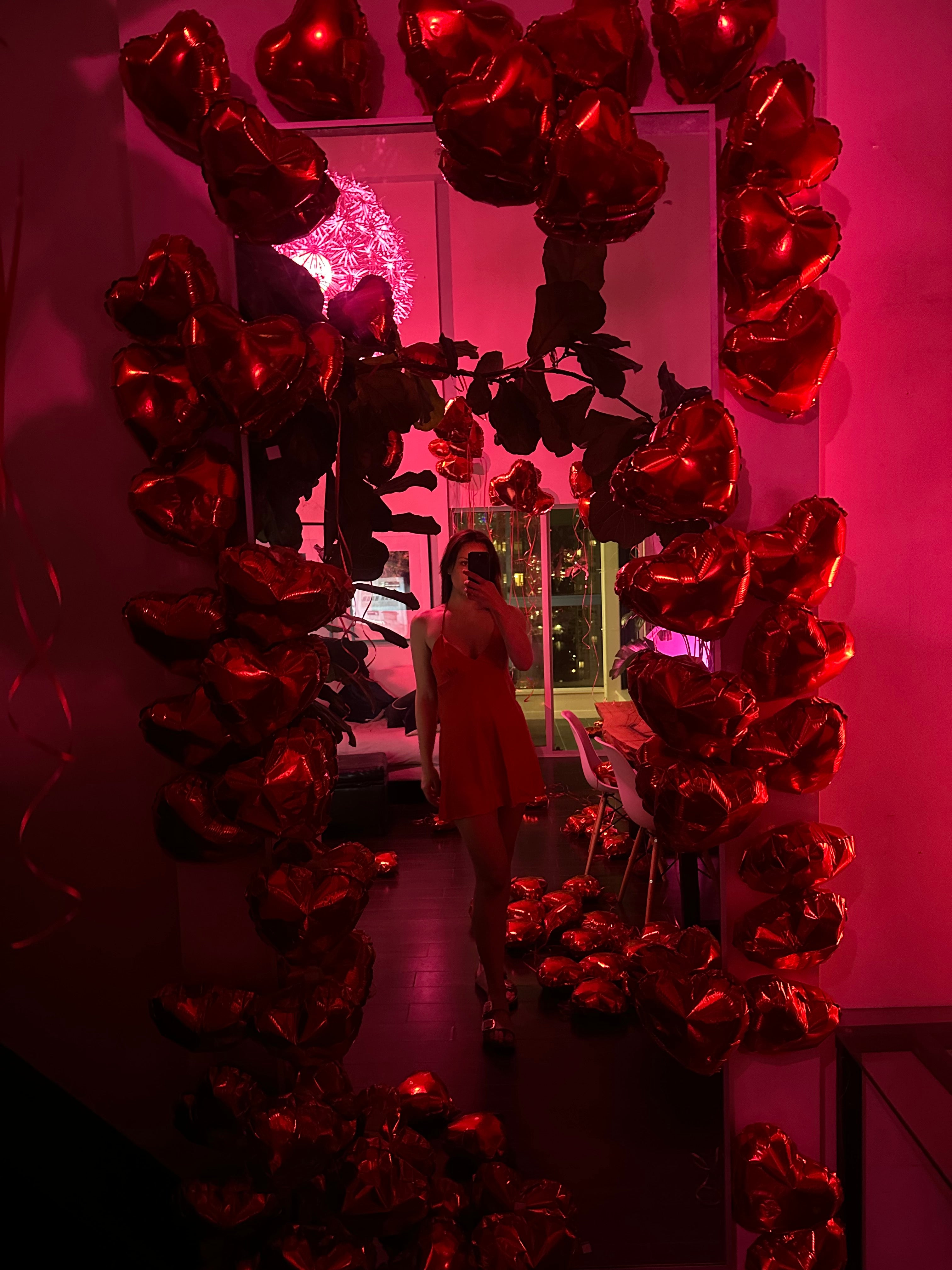 Red heart-shaped balloons arranged in a circular pattern with a blurred background.