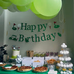 Birthday party setup with balloons, cake, and snacks on a table.