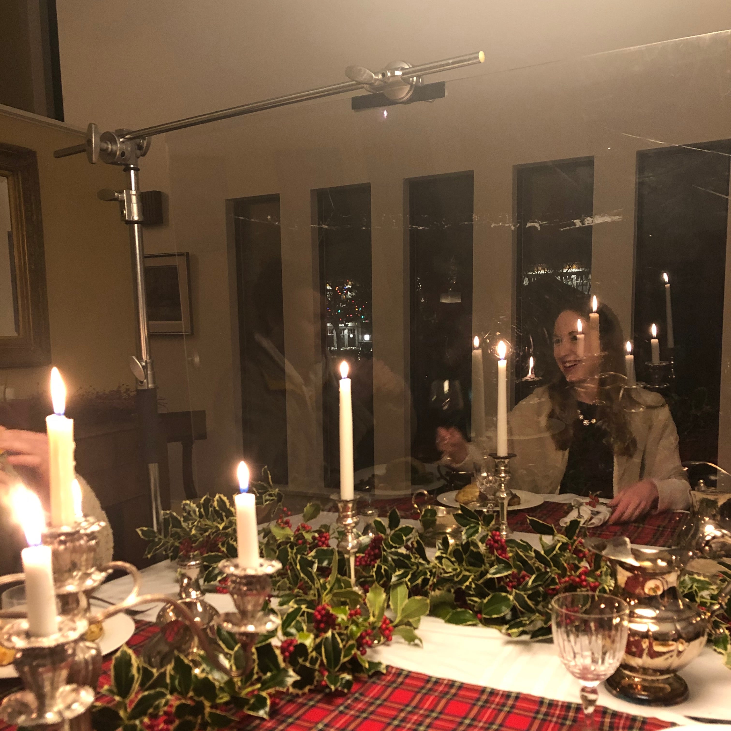 Dining table set with candles, glasses, and a plaid tablecloth.