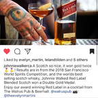 Johnnie Walker Red Label whisky bottle with a cocktail and tattooed hand on a bar counter.