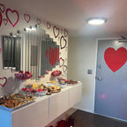 Dessert table with various treats in a room decorated with heart shapes on the wall and door.