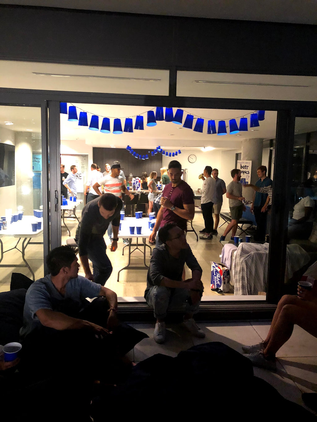 People gathered in a room with tables and chairs, decorated with blue streamers.