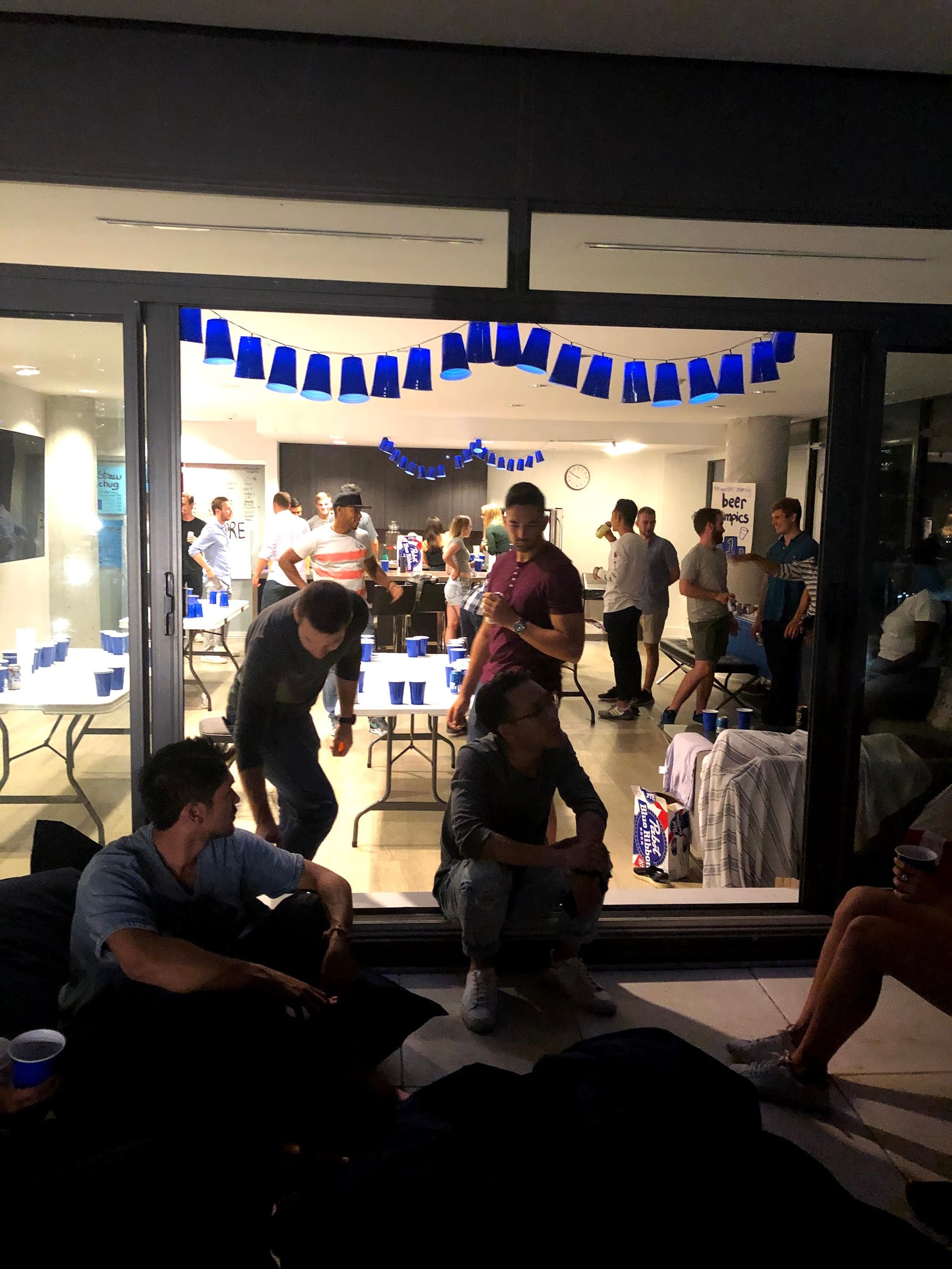People gathered in a room with tables and chairs, decorated with blue streamers.