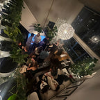 People gathered in a modern indoor setting with plants and a chandelier.