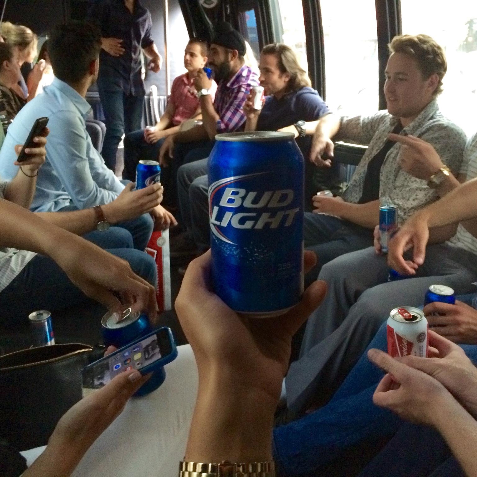 People on a bus holding Bud Light beer cans