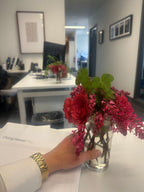 Person holding a vase of red flowers in an indoor corporate office setting