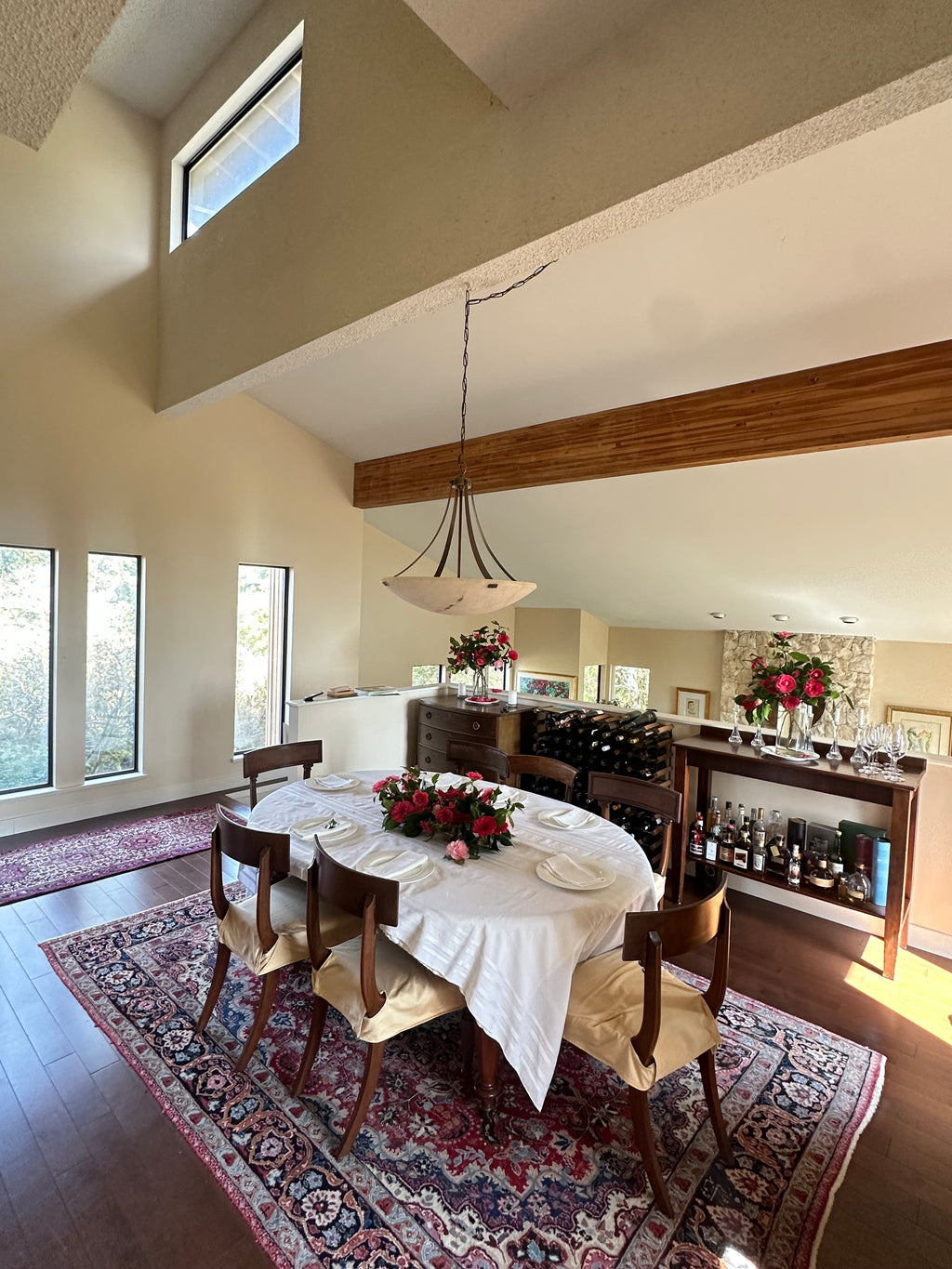 Dining room with a table set for a meal, chairs, and a decorative rug.