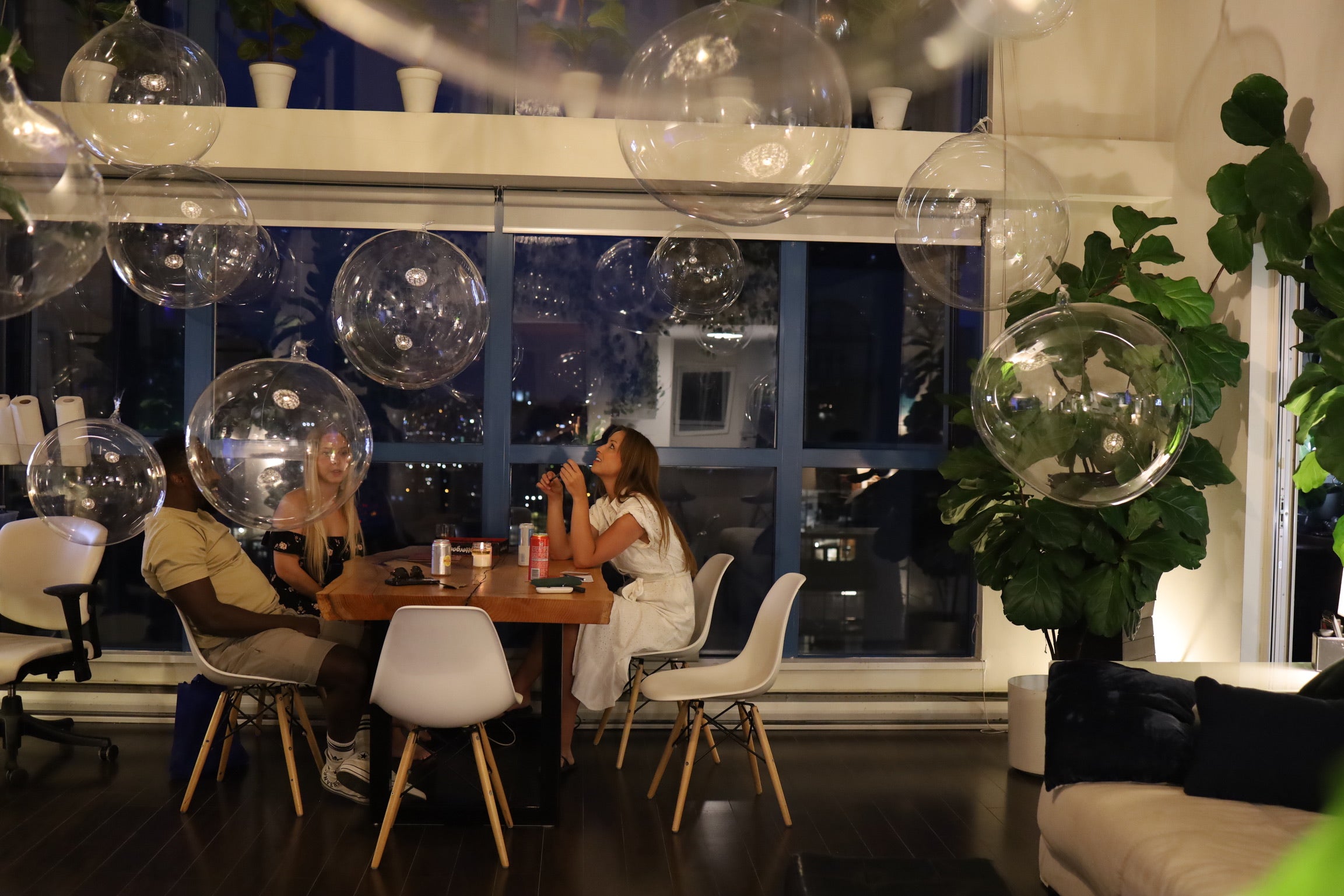 People sitting at a table with large transparent bubbles in a modern interior setting.