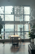 Modern interior with large windows, a table, chairs, and decorative plants.