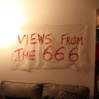 Poster with 'Views from the 666' text on a wall in a room with people and decor.