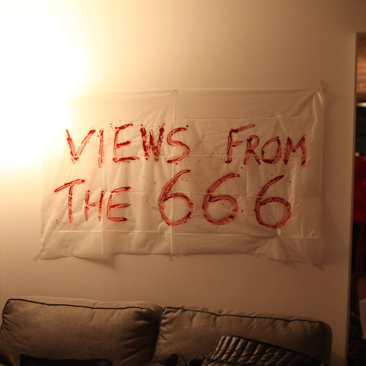 Poster with 'Views from the 666' text on a wall in a room with people and decor.