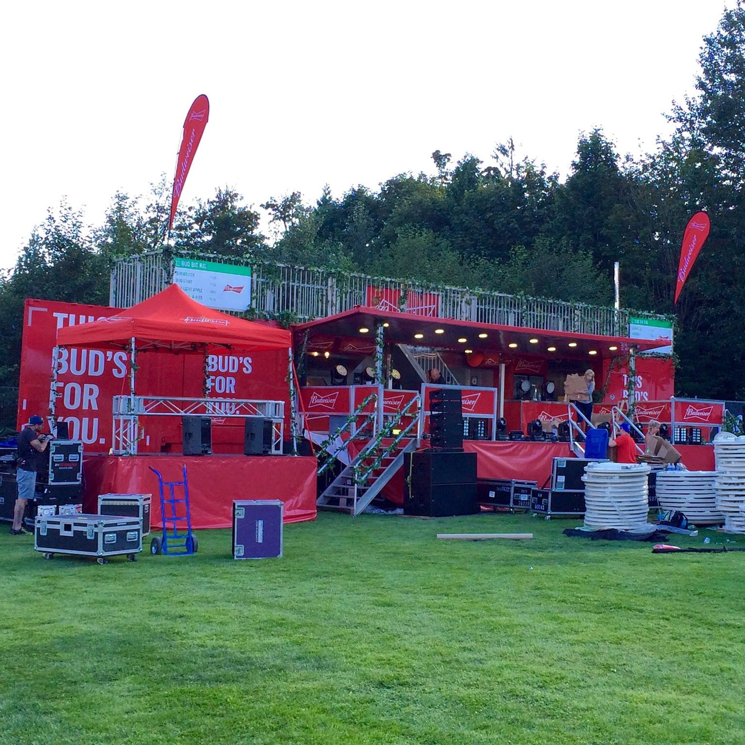 Red event booth with 'Bud's for You' branding on a grassy area with trees in the background.