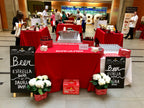 Red tables with beer bottles and Estrella Damm branding in a public area.