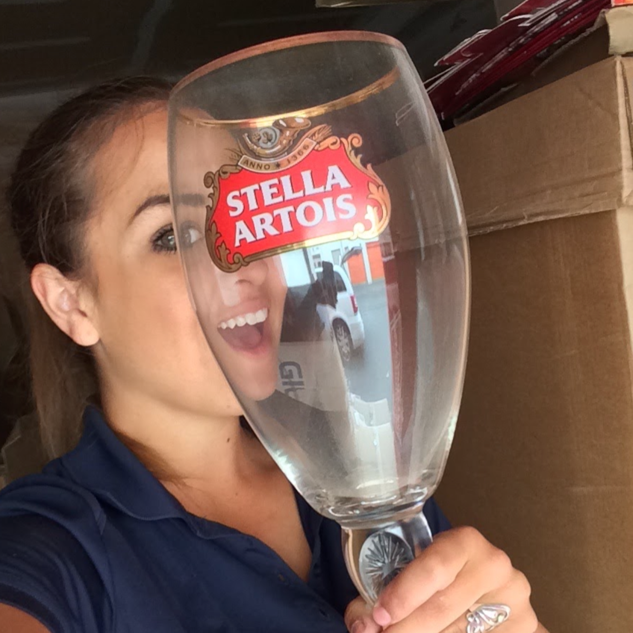 Person holding a large Stella Artois glass in front of a cardboard box.