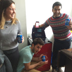 Three people holding blue cans in a casual indoor setting