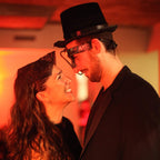 Two people in formal attire with a warm, red-toned background