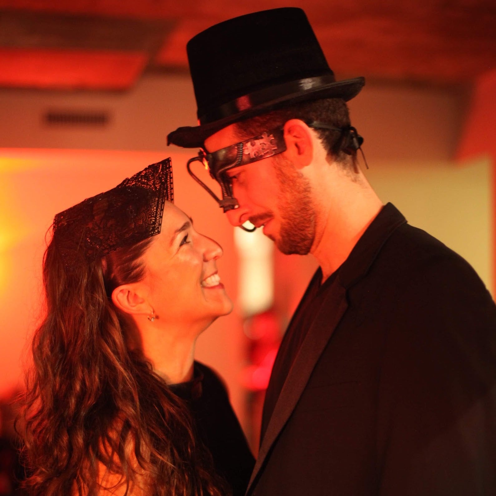 Two people in formal attire with a warm, red-toned background