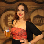 Woman holding a bud light beer in front of wooden barrels with 'Stanley Park' branding.