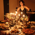 Woman in a dark room with candles and a table full of food