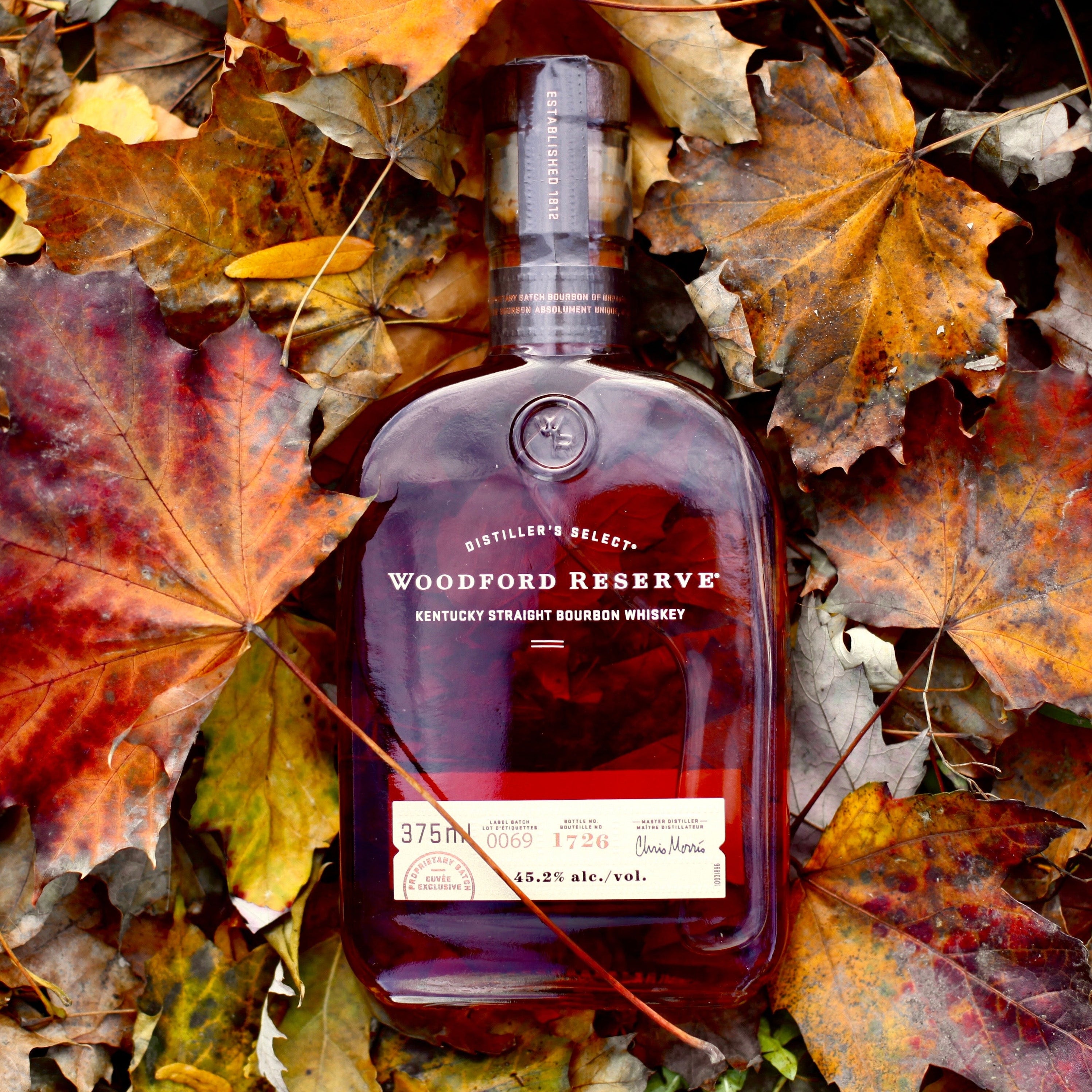 Woodford Reserve bourbon bottle on a bed of autumn leaves shot by Evelyn Martin directionless creative