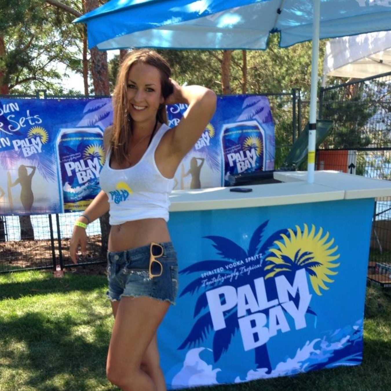 Woman posing in front of a Palm Bay branded booth at an outdoor event.